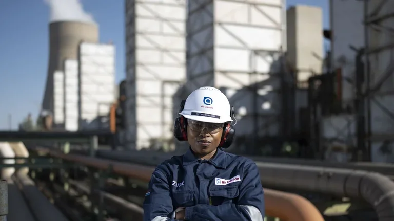 An Air Liquide employee wearing a helmet and standing in front of a plant
